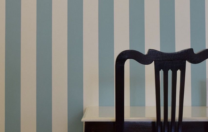 A view of a work desk and chair placed against a pastel blue and white striped wall | Dileep  Kothi, Jaipur